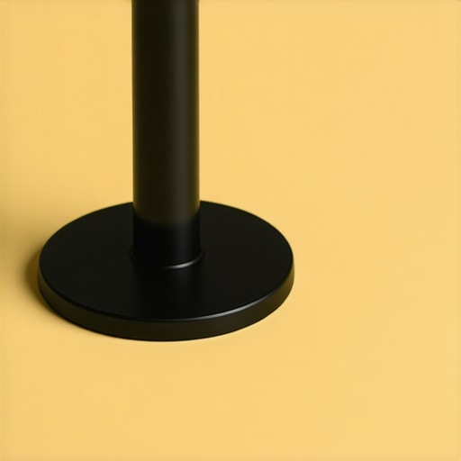 Close-up of a matte black steel microphone boom base with rubber feet and screw holes for clamp attachment